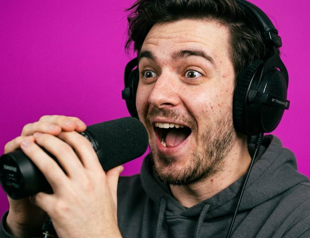 A delighted podcaster with headphones and a microphone, representing Manchester's top podcast studio hire options.