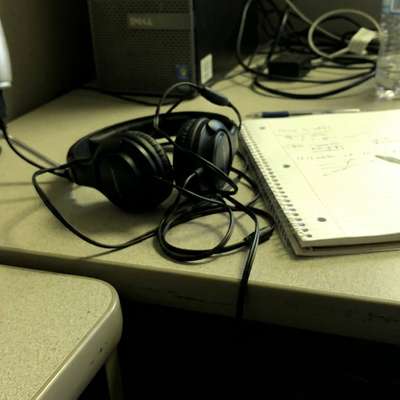A desk setup with a microphone, headphones, and notebook for capturing ideas from thought leadership podcasts.
