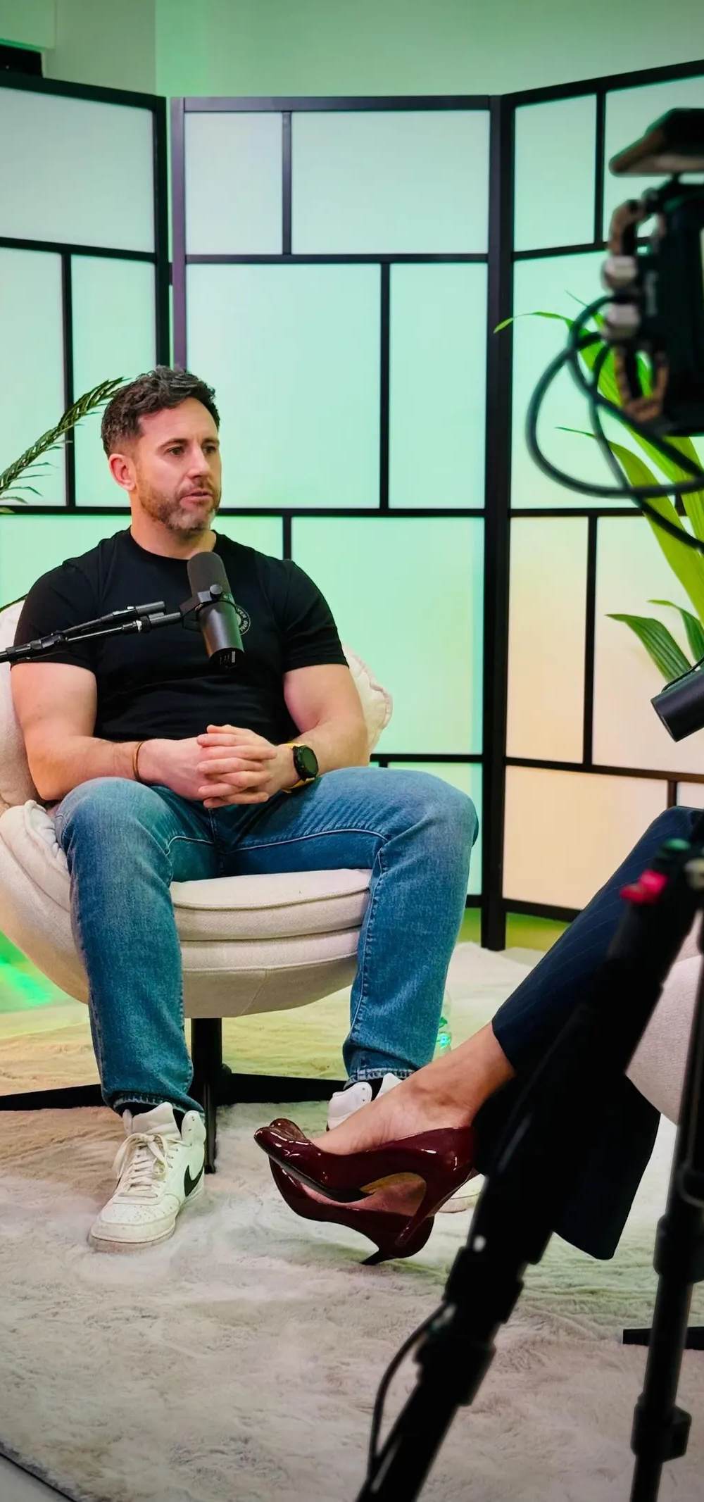 A corporate video shoot in progress: director's monitor in the foreground showing a business interview being filmed on a lit studio set.