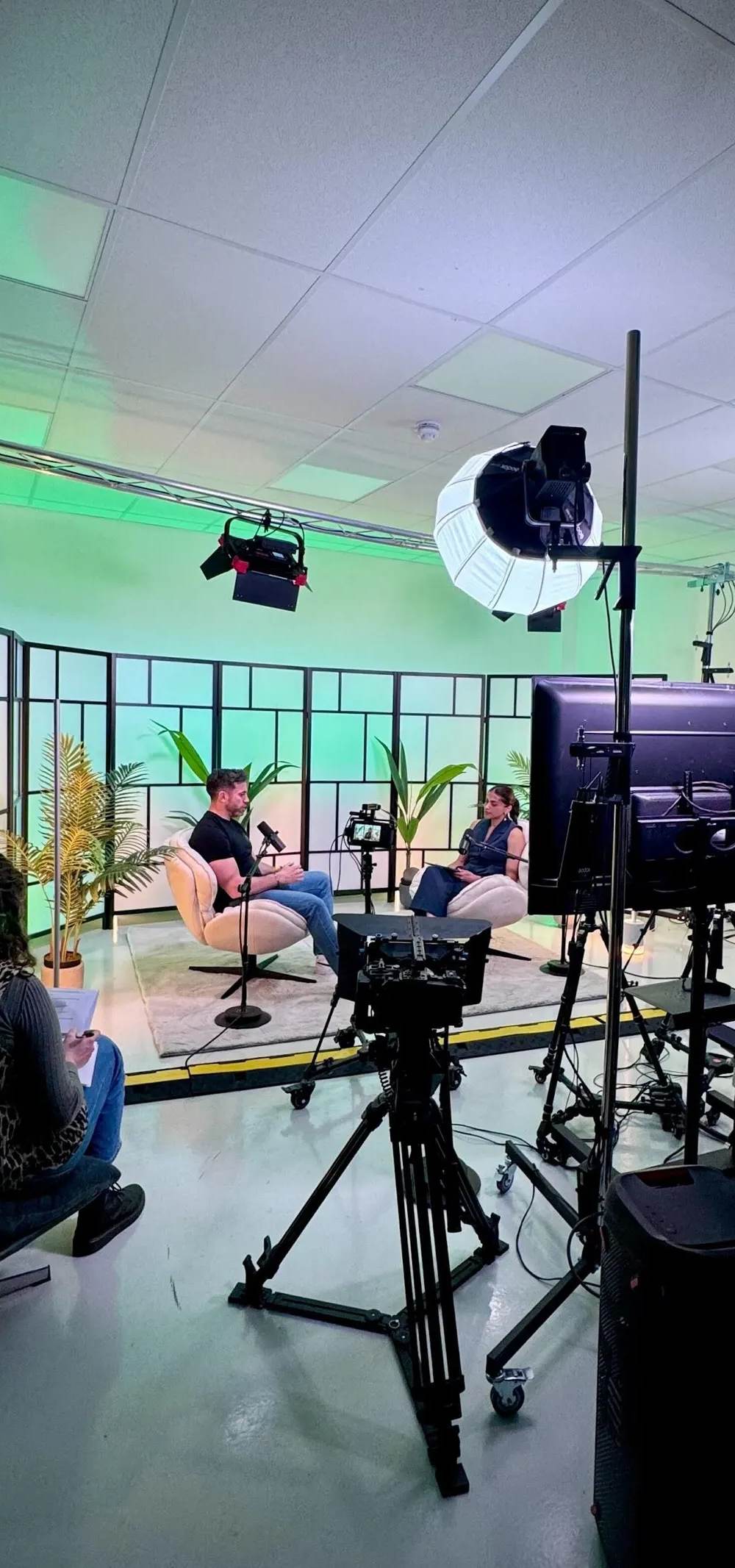 Film crew adjusting cameras and lighting on a corporate video shoot in a UK studio.
